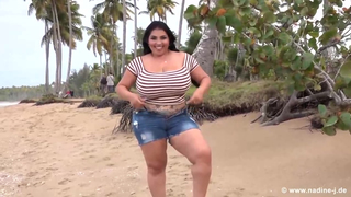 Busty brunette, Isabella is posing topless on the beach and playing with her massive milk jugs